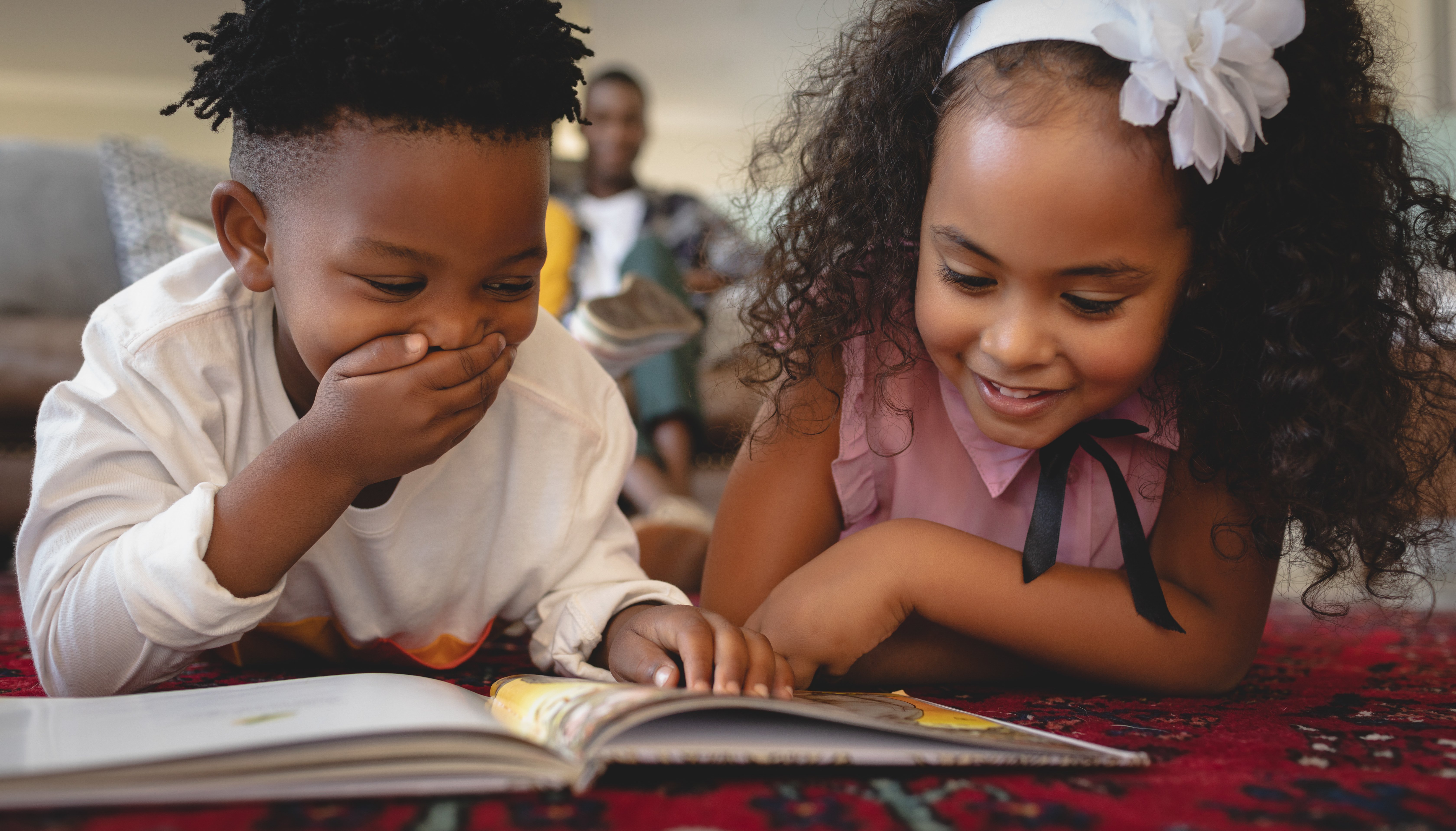 Girl and boy reading a book together and smiling and laughing